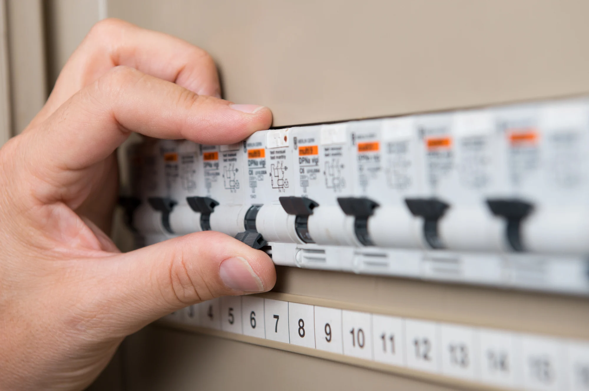 Electrician checking labelled circuit breakers in a residential switchboard